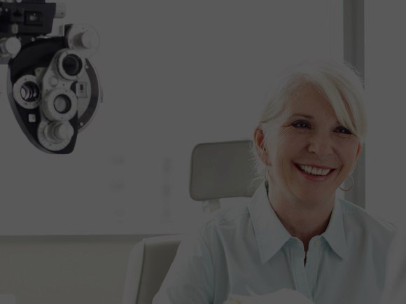 Smiling woman in front of optometrist equipment