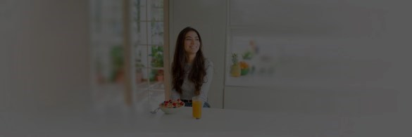 Smiling woman with glass of orange juice in kitchen