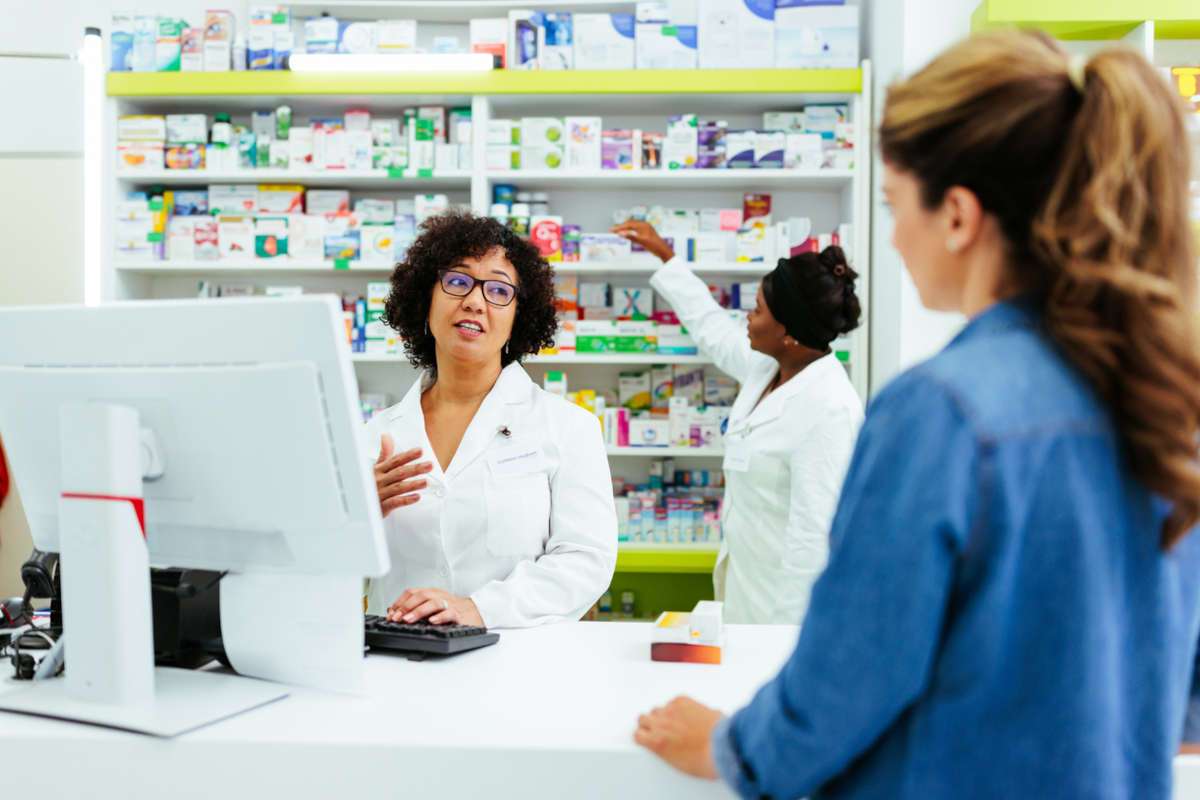 Woman consulting pharmacist behind counter